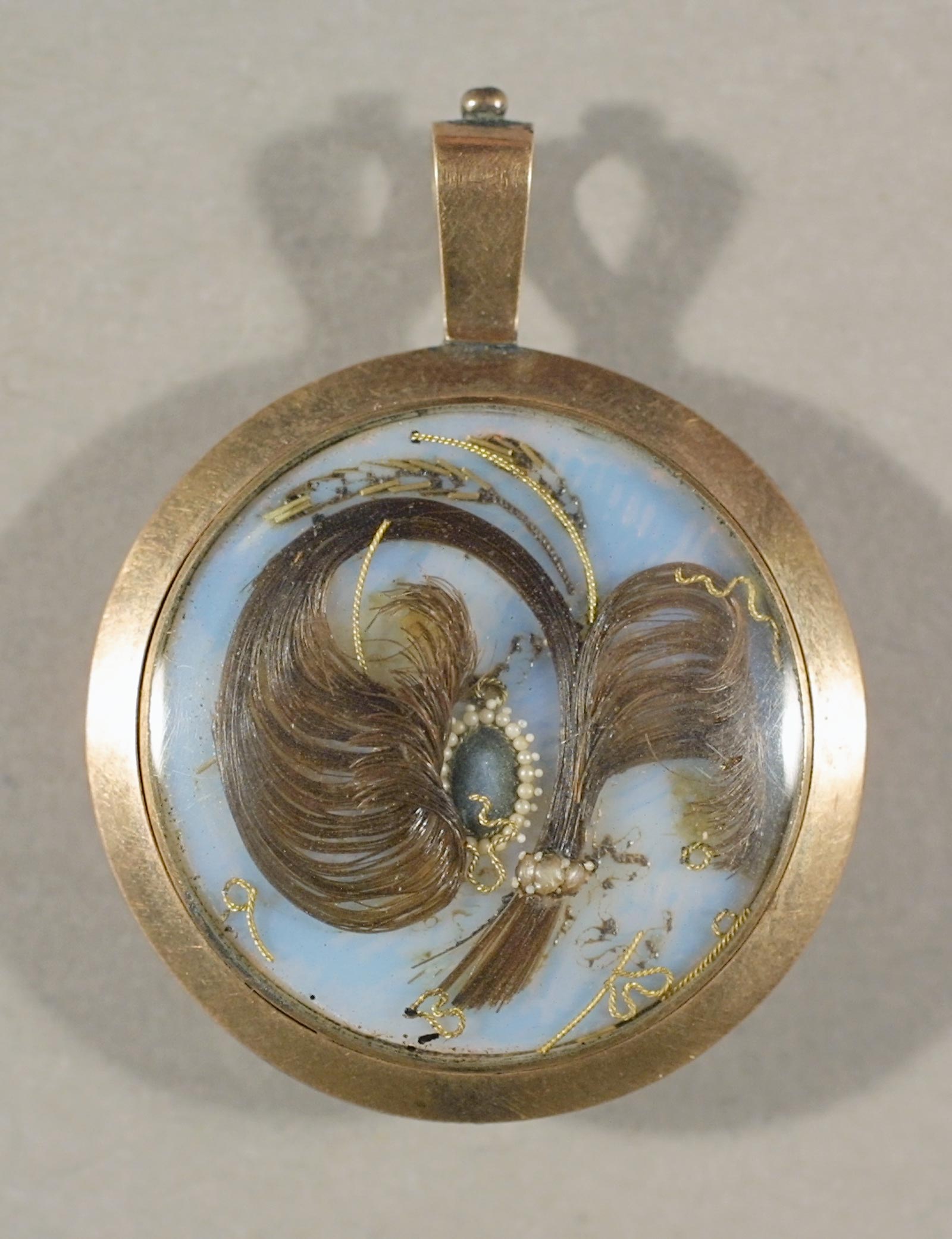 Hairwork locket set with gold initials “JD,” ca. 1800. Gold, glass, human hair, pearls, 1 7⁄16  x 1 1⁄16 x ¼ in. Historic New England, Gift of Mrs. Paul G. Pennoyer, 1965.82.